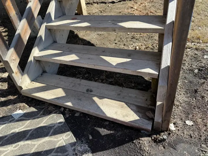 Weathered deck stair treads with stringers in ground contact, Red Deer Alberta