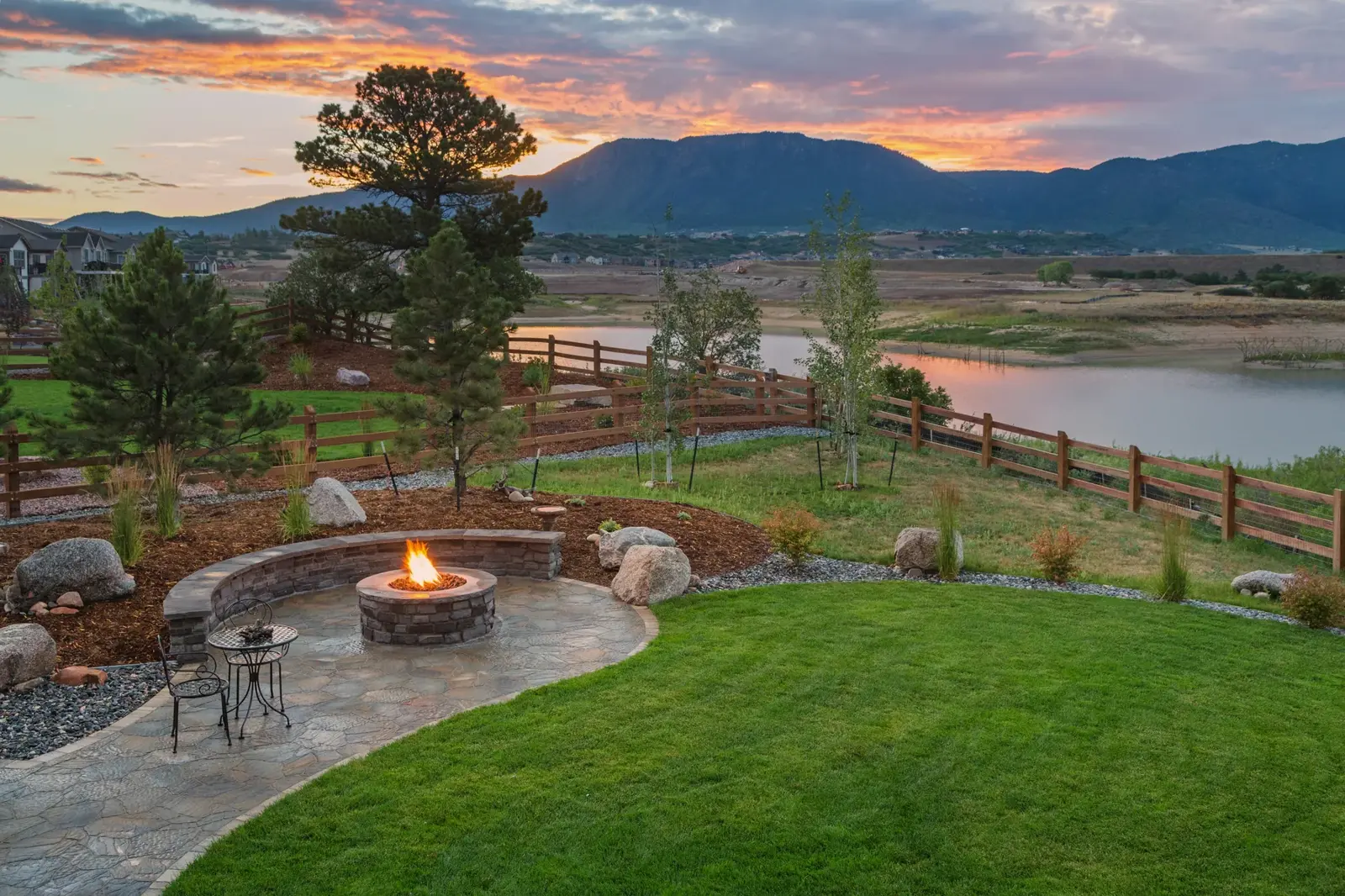 Flagstone patio with a curved stone seat wall and a gas fire pit, overlooking open country at sunset