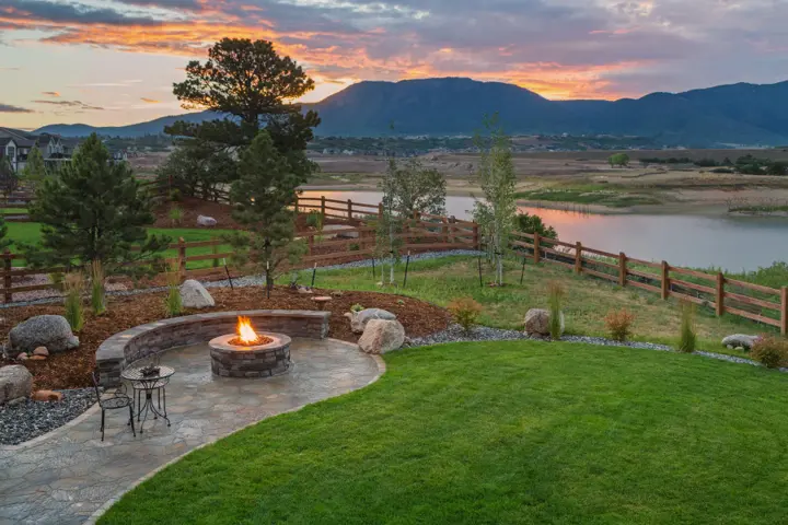 Flagstone patio with a curved stone seat wall and a gas fire pit overlooking open country