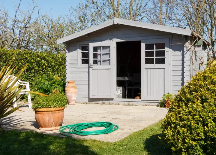 Grey garden shed with both doors open showing storage inside, sitting on a paved patio slab
