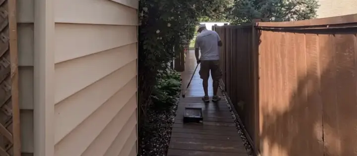 Green Ladder Contractors crew member staining a deck walkway in Red Deer, Alberta