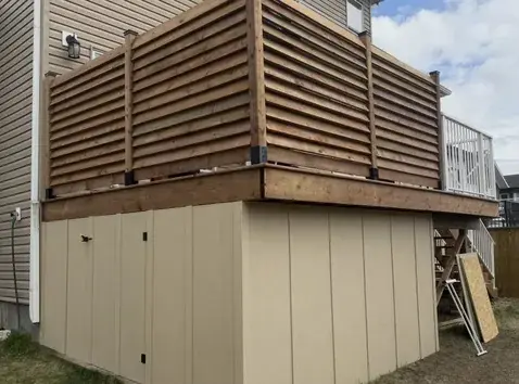 Cedar louvred privacy wall wrapping a raised deck in Red Deer, Alberta, built by Green Ladder Contractors