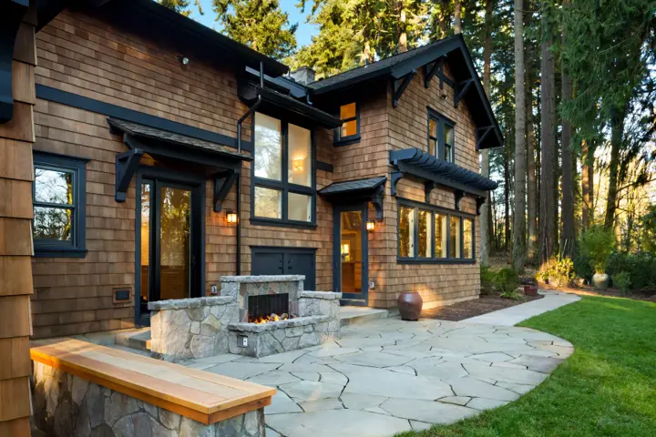 Stone outdoor fireplace built into a flagstone patio with a cedar-capped stone bench