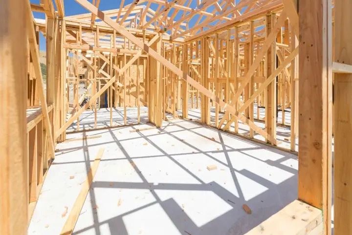 Interior of a framed structure with engineered roof trusses set overhead and diagonal let-in bracing running across the stud walls